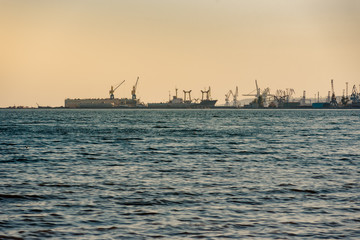 Silhouette of port cranes and ships at sunset in evening light