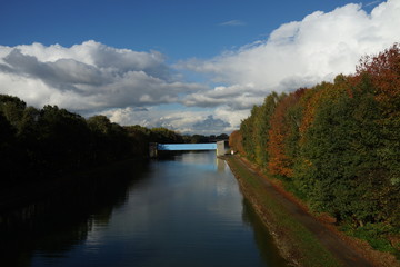 Fototapeta na wymiar Blick auf den Dortmund-Ems-Kanal, im Hintergrund eine blaue Brücke, beidseits Wald