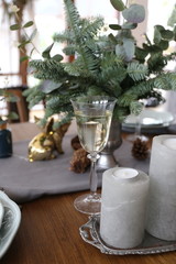 Elegant Christmas tree with gifts in the living room with dinner table near the textured gray walls in luxury apartments. 