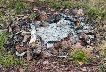Naklejka na ściany i meble extinguished fireplace with ash and remains of wood lined with stones on the ground in a circle