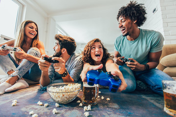 Group of friends play video games together at home, having fun.