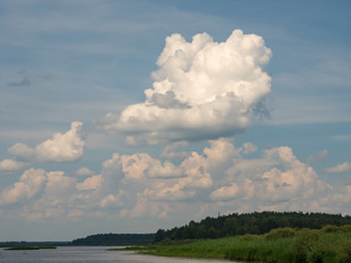 Naklejka na ściany i meble clouds above lake and green forest