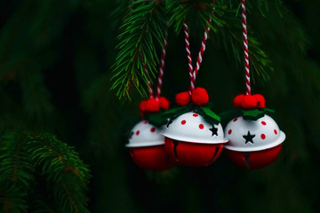 three red and white bells on the Christmas tree