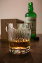 a glass and a bottle of whisky on wooden table