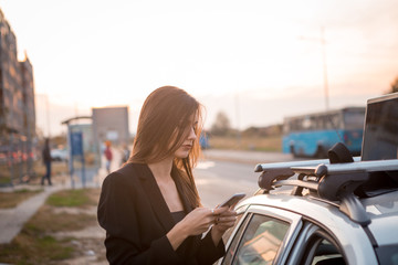 A beautiful young, tired businesswoman writes a message on her phone.