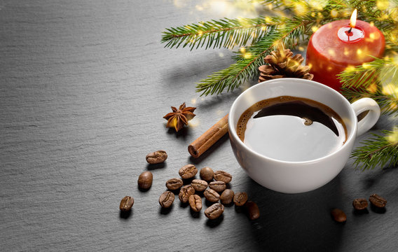 Coffee cup and coffee beans with christmas decoration on black stone plate.