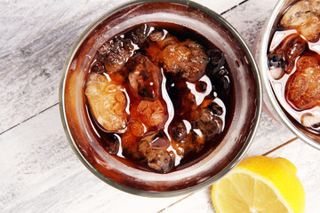 Softdrink with ice cubes, lemon and straw in glass