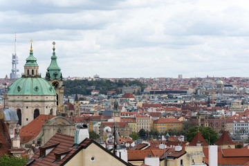Naklejka na ściany i meble Prague panorama with colorful rooftops on a cloudy day, with The Church of St. Nicholas and Zizkov television tower in the distance