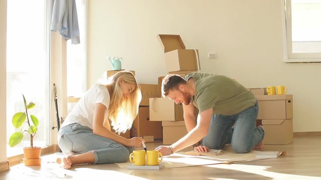 Young couple in new apartment unpacking cardboard boxes