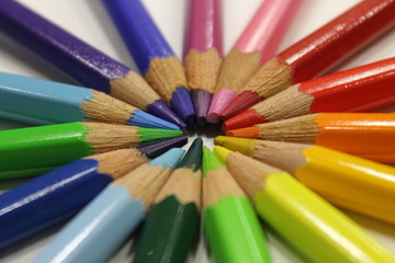 colored pencils lying around the heart on a white background
