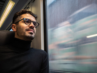 young man with glasses traveling by train