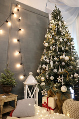 christmas decorated room with Edison lamps, gift boxes under the new year tree near the grey wall 