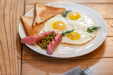 Breakfast food. American style breakfast with fried eggs, sausage, green peas and toast. The concept of a healthy morning.