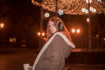 The portrait of an young redhear lady on the evening wearing earmuffs