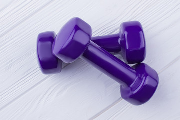 Pair of purple dumbbells on white background. Hand weights on wooden surface. Best fitness gift.