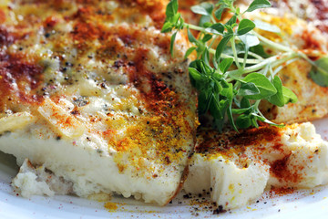 Scrambled eggs or omelette made from eggs and cheese with onion, herbs, peppers mix, curcuma, paprika and basil branch on the plate