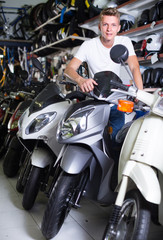 Fototapeta na wymiar Portrait of male motorcyclist sitting on the bike in the store