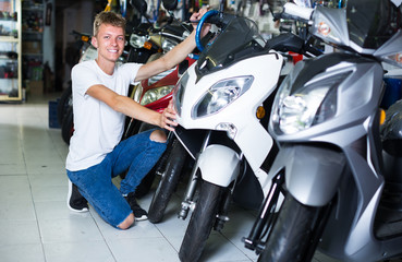 Fototapeta na wymiar happy man motorcyclist choosing the bike in the shop