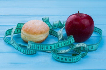 Donut, apple and measuring tape. Healthy eating and junk food. Diet and weight loss.