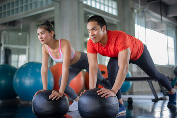 Attractive sports people are working out with fitness balls in gym