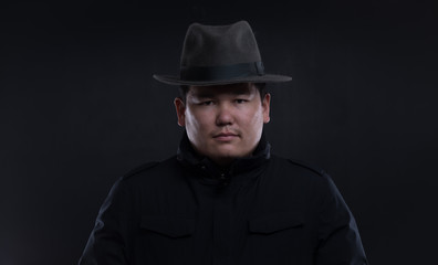 classic portrait of asian man in hat on black studio background