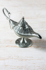 Silver aladdin's lamp on a white wooden background. Ramadan concept.