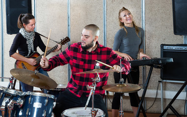 Rehearsal of music group with male drummer