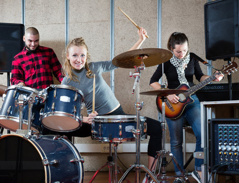 Music band with smiling girl drummer rehearsing
