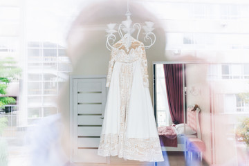 photographer looks through the window and photographed wedding dress. wedding dress hanging on a chandelier