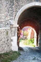 A woman in a dress is climbing a brick wall.