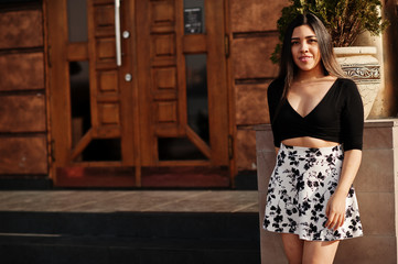 Pretty latino model girl from Ecuador wear on black tops and skirt posed at street.