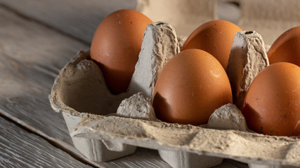Chicken eggs in cardboard rack or egg box on white table.
