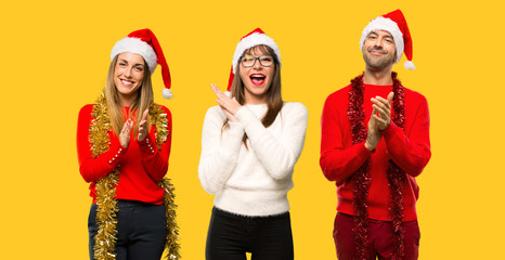 A group of people Blonde woman dressed up for christmas holidays applauding after presentation in a conference on yellow background