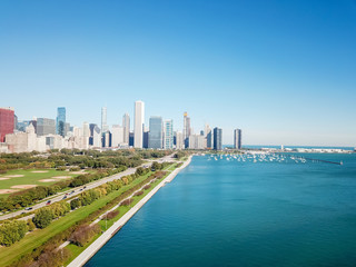 Aerial view of downtown Chicago tall skylines from Grant Park. Tranquil Michigan Lake and green trees along Lake Shore Drive, row of docked boats and yachts on the background