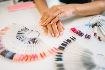 Well-groomed female hands against nail sample fan