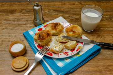 Traditional Bosnian pastry- manti borek with cheese on wooden table with yogurt. rustic background with low light and old bowls.