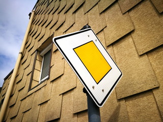 Verkehrszeichen mit Hinweis auf die Vorfahrtsstraße vor der Fassade eines Altbau mit eckigen...