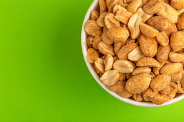 Roasted peanuts in paper cup on bright green background