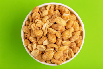 Roasted peanuts in paper cup on bright green background
