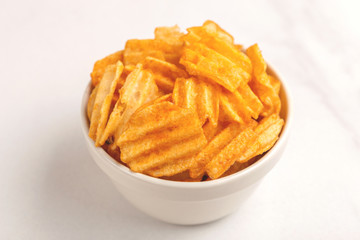 Crunchy corrugated potato chips in white bowl
