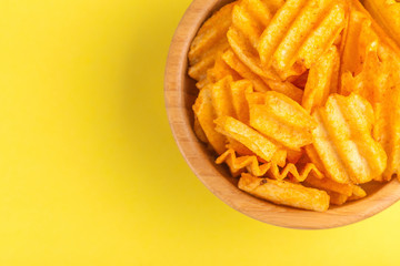 Crispy corrugated potato chips in wooden bowl