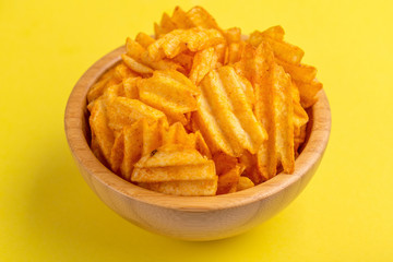 Crispy corrugated potato chips in wooden bowl