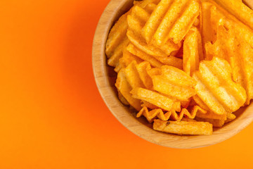 Crispy corrugated potato chips in wooden bowl
