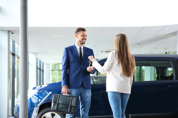 Salesperson giving car key to man in auto dealership