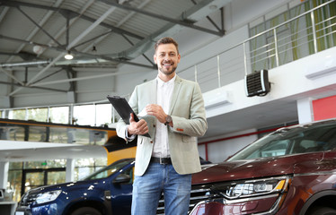 Salesman with clipboard in modern car dealership