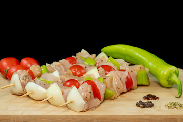 Chicken Shish Kebab with tomato, onion and green peppers on wood with isolated black background