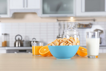 Cornflakes with glasses of juice and milk on kitchen table