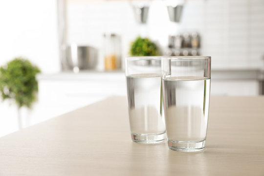 Glasses of fresh water on table indoors. Space for text