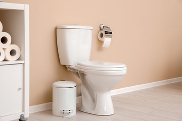 Holder with toilet paper roll on wall in bathroom