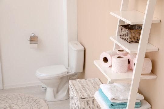 Toilet paper rolls on shelving unit in bathroom. Space for text